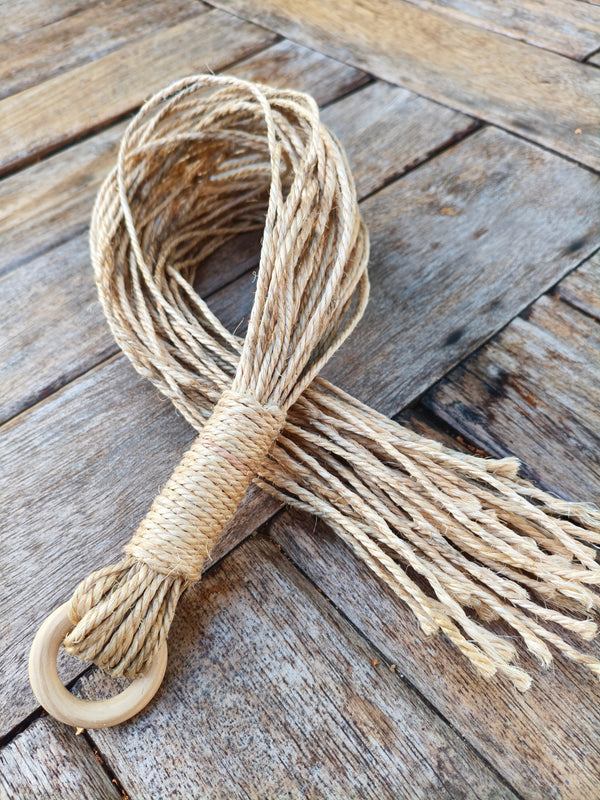 Martinet doux AdryX en 48 fils de jute, 63 cm, posé en boucle sur une table en bois, poignée ligaturée et anneau en bois