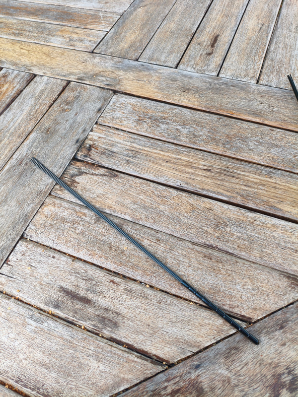 Badine AdryX en carbone, 50 cm, fine et légère, posée en diagonale sur une table en bois