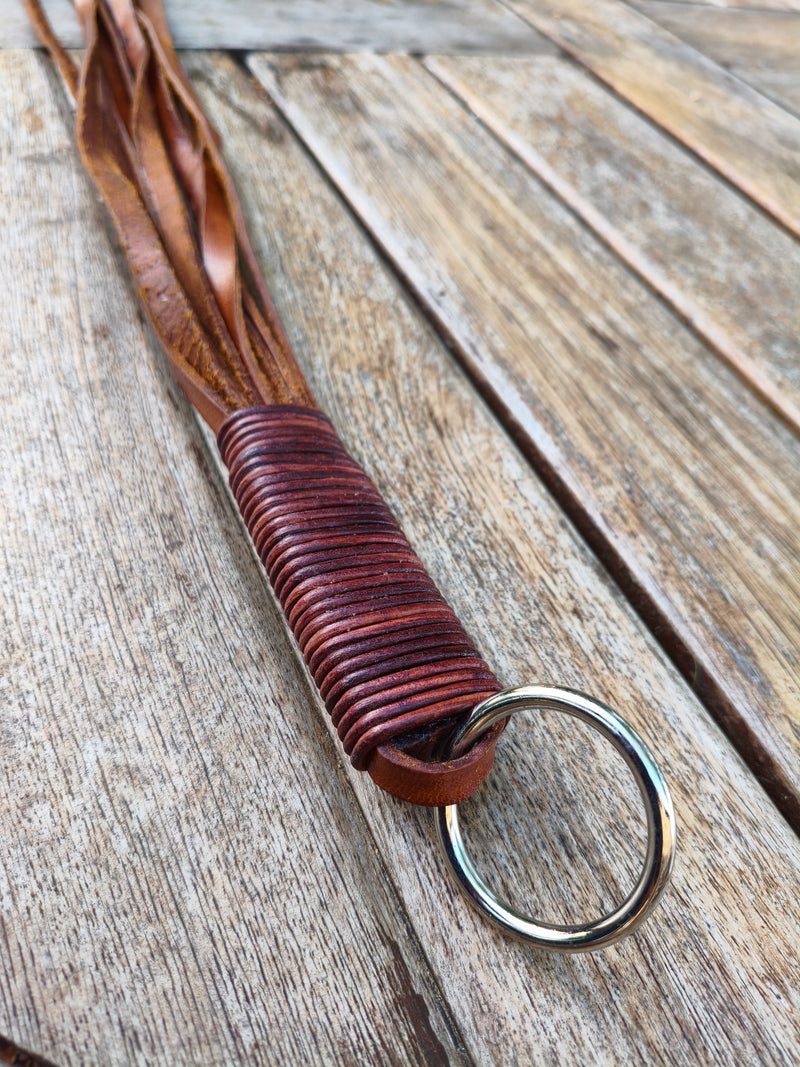 Détail de la poignée du martinet AdryX : ligature en cuir et anneau métallique, fait main en France