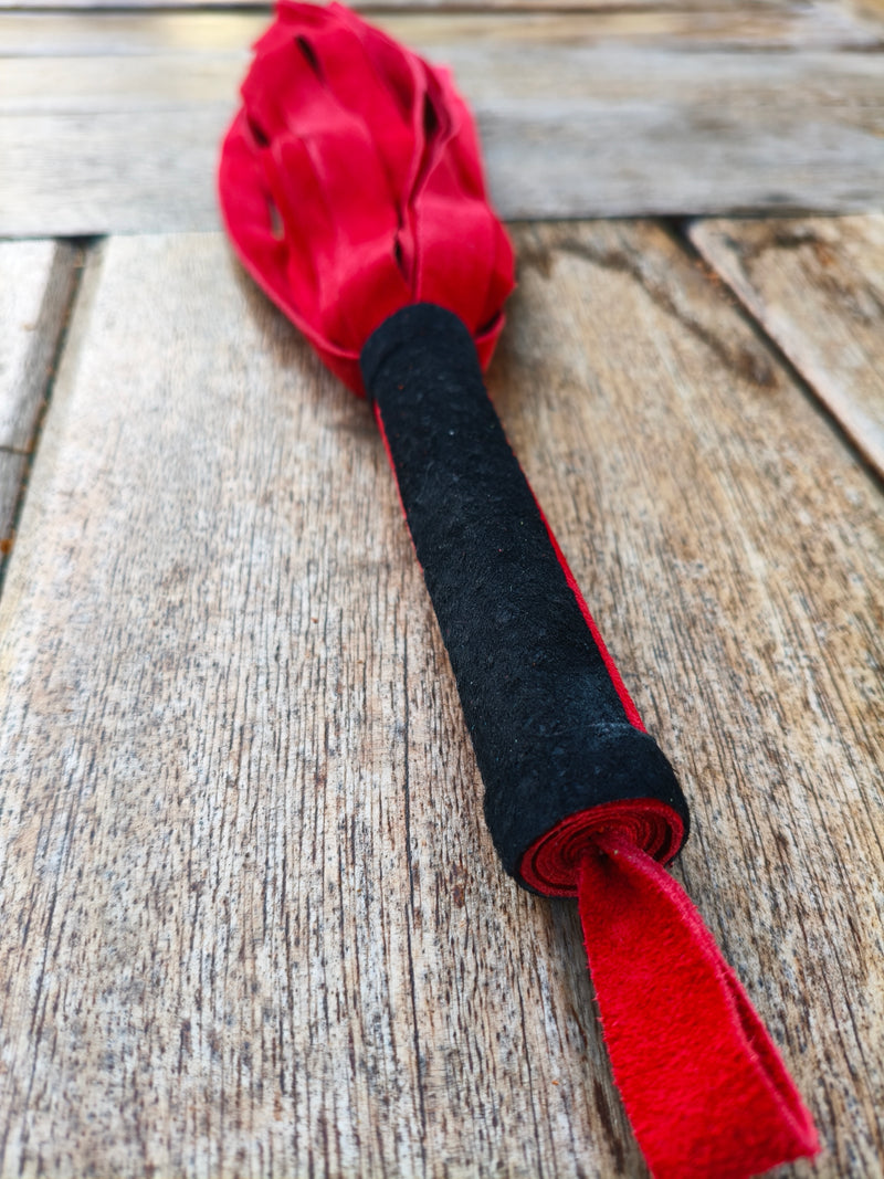 Détail de la poignée rouge à bande noire et de la dragonne du martinet doux AdryX, fait main en France