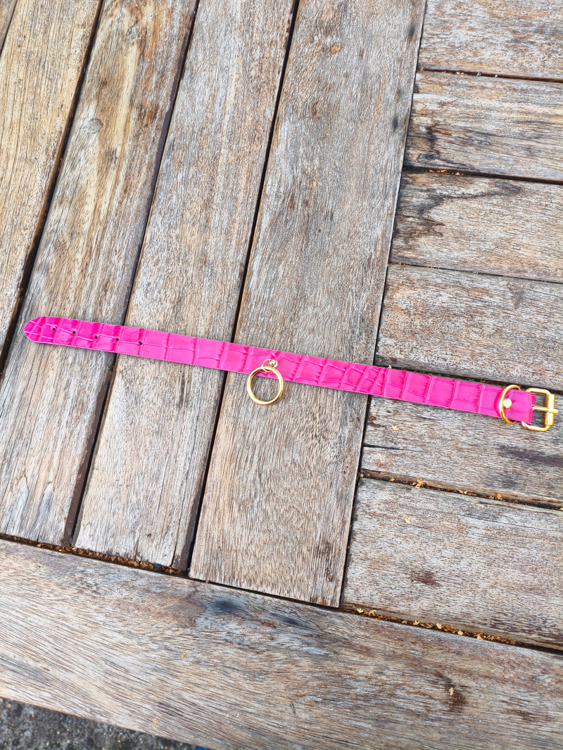 Collier fuchsia croco AdryX posé à plat sur une table en bois, anneau et fermoir dorés