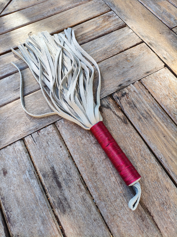 Martinet AdryX en cuir pleine fleur bicolore, lanières grises et manche ligaturé rouge, 56 cm, posé sur une table en bois