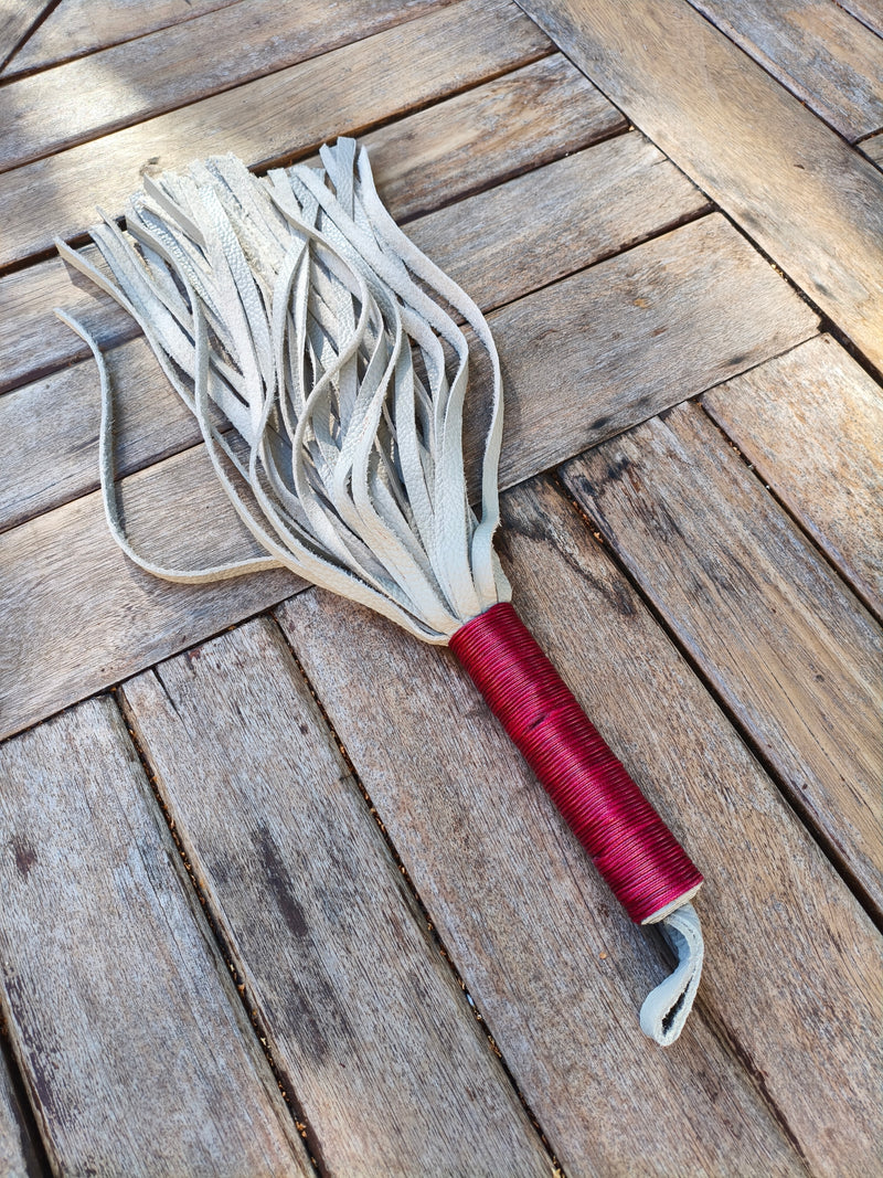 Martinet AdryX en cuir pleine fleur bicolore, lanières grises et manche ligaturé rouge, 56 cm, posé sur une table en bois