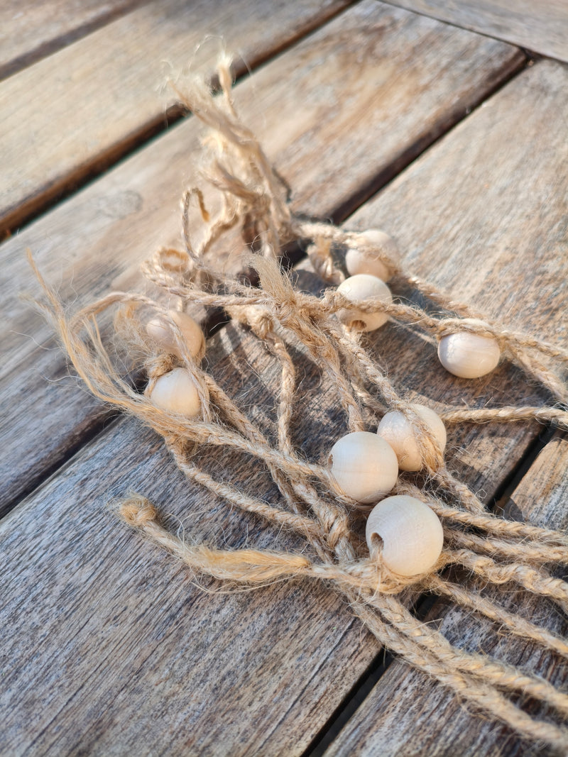 Gros plan sur les perles en bois et les fils de jute naturel du martinet AdryX, fait main en France