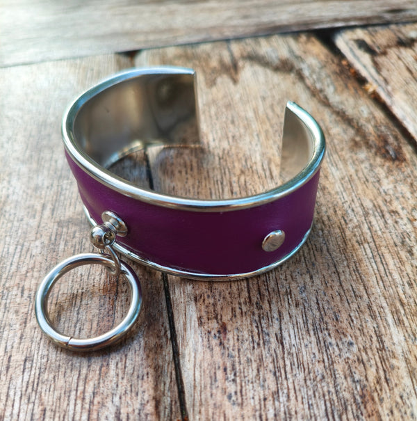 Bracelet manchette AdryX en cuir prune à monture argentée, anneau central mobile, posé sur une table en bois