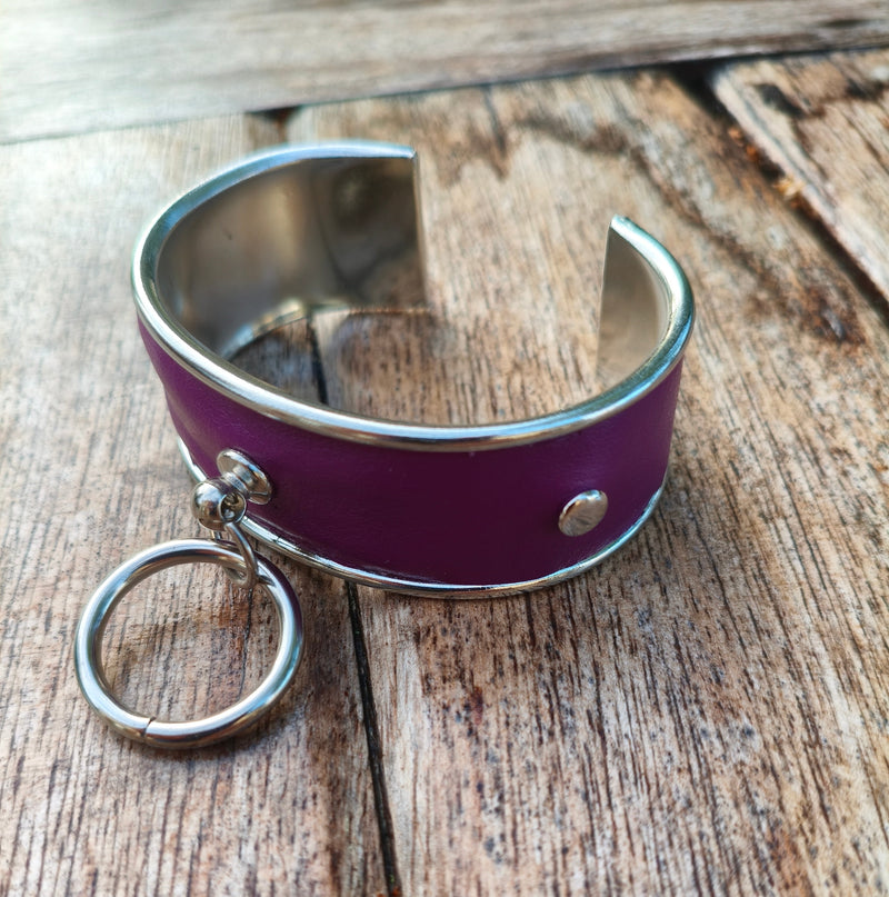 Bracelet manchette AdryX en cuir prune à monture argentée, anneau central mobile, posé sur une table en bois