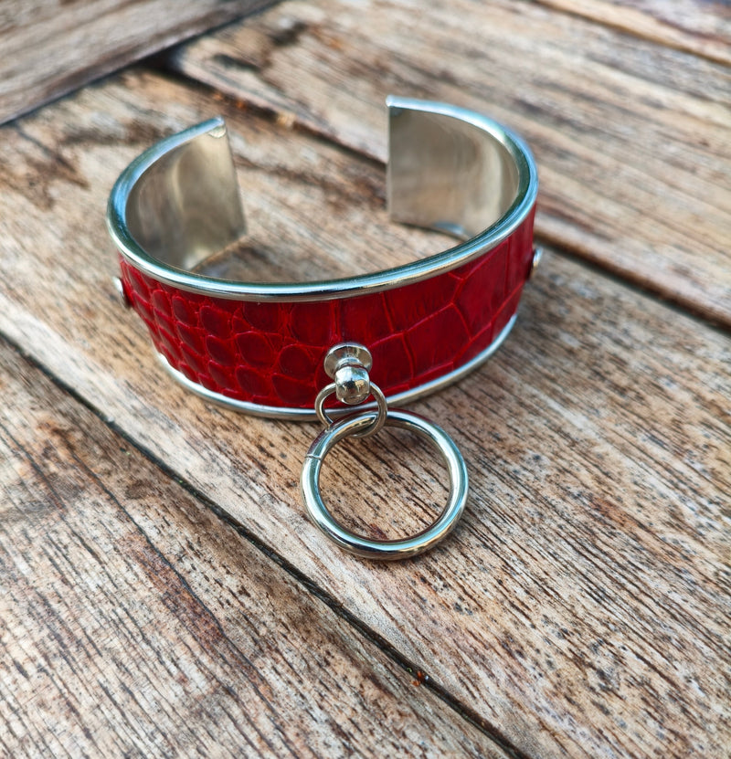 Bracelet manchette AdryX en cuir rouge effet crocodile à monture argentée, anneau mobile, posé sur une table en bois