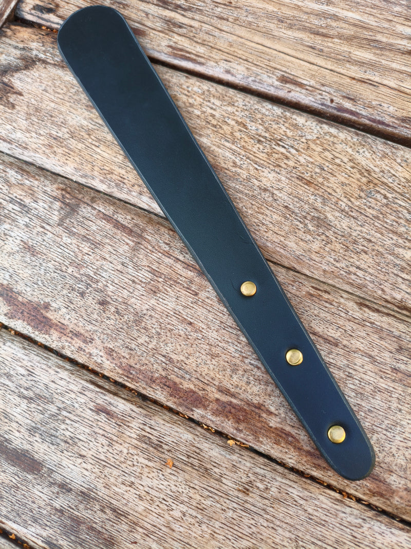 Paddle en cuir noir AdryX et ses trois rivets en laiton, plan rapproché