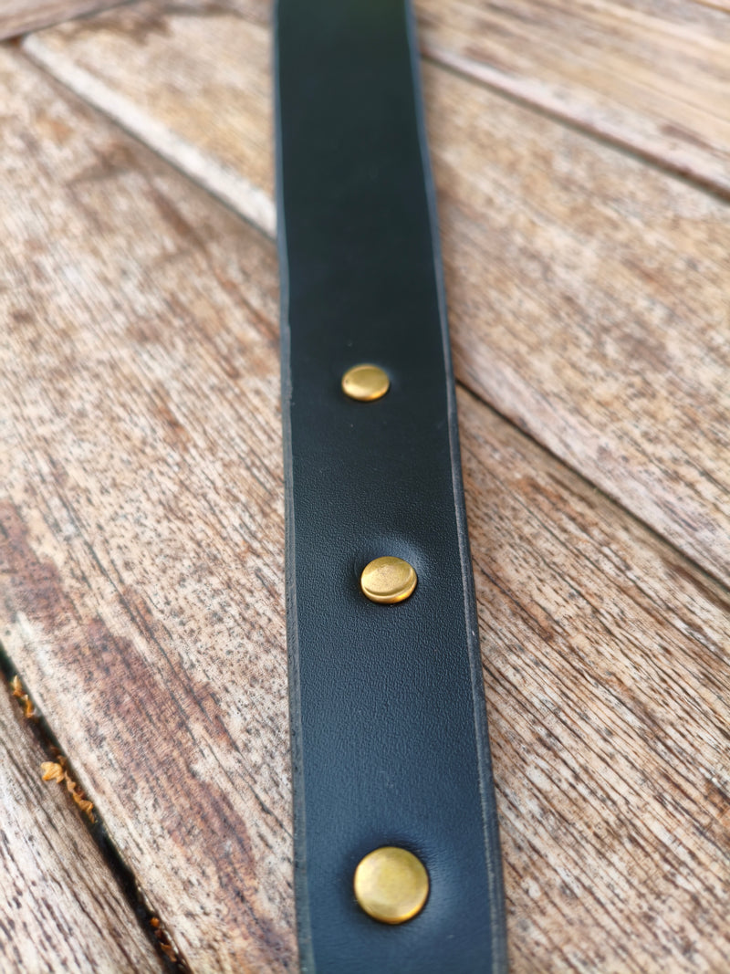 Gros plan sur les trois rivets en laiton du manche du paddle en cuir noir AdryX, fait main en France
