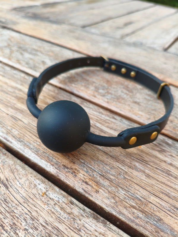 Bâillon boule La Retenue AdryX – boule en silicone noir mat et attaches rivetées en laiton